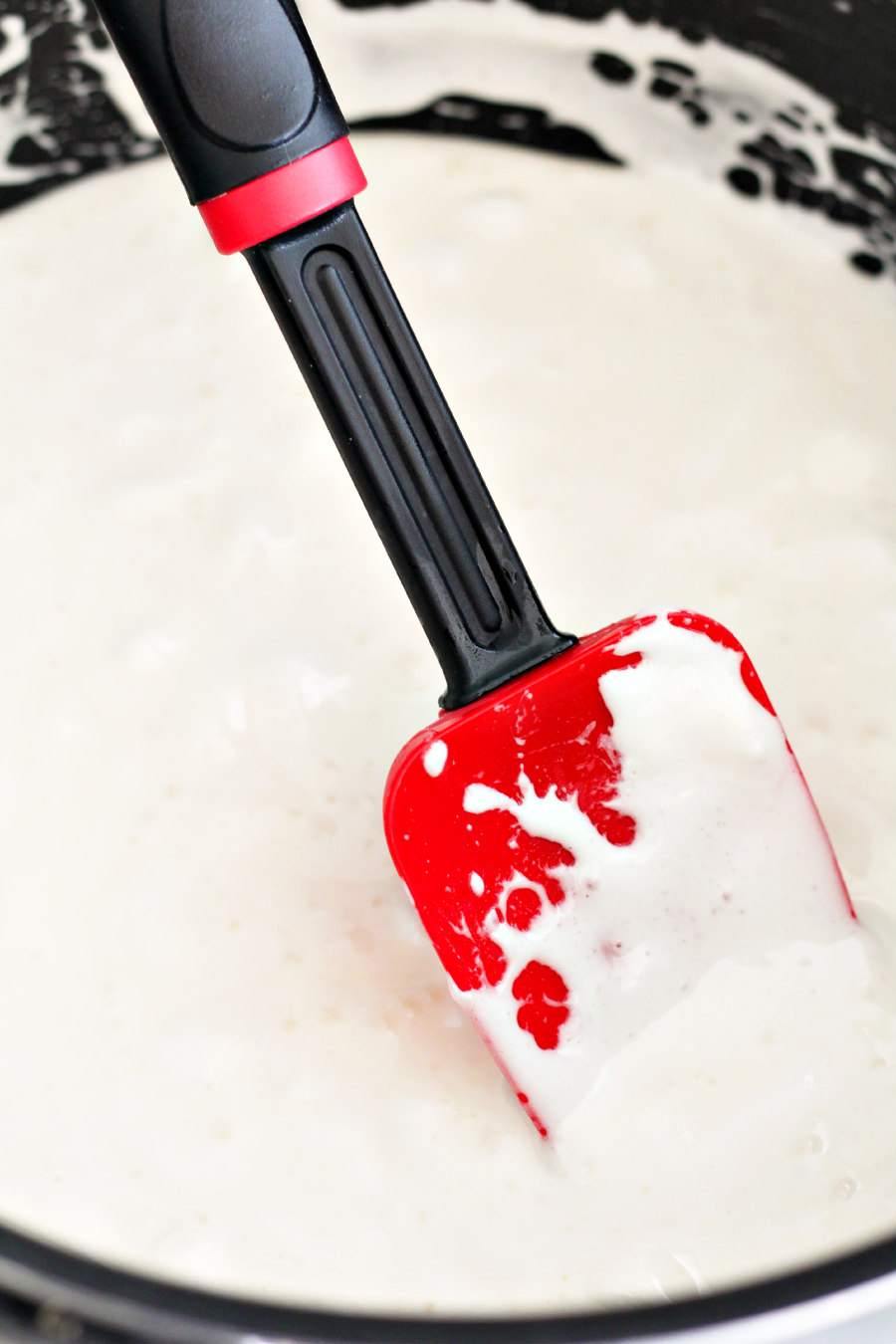 Melted marshmallows and butter with bourbon in a large pot with a rubber spatula.