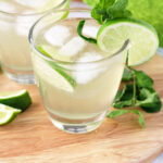 Two Irish Mule Cocktails garnished with lime slices and fresh mint sitting on a round board with lime wedges and fresh mint leaves.
