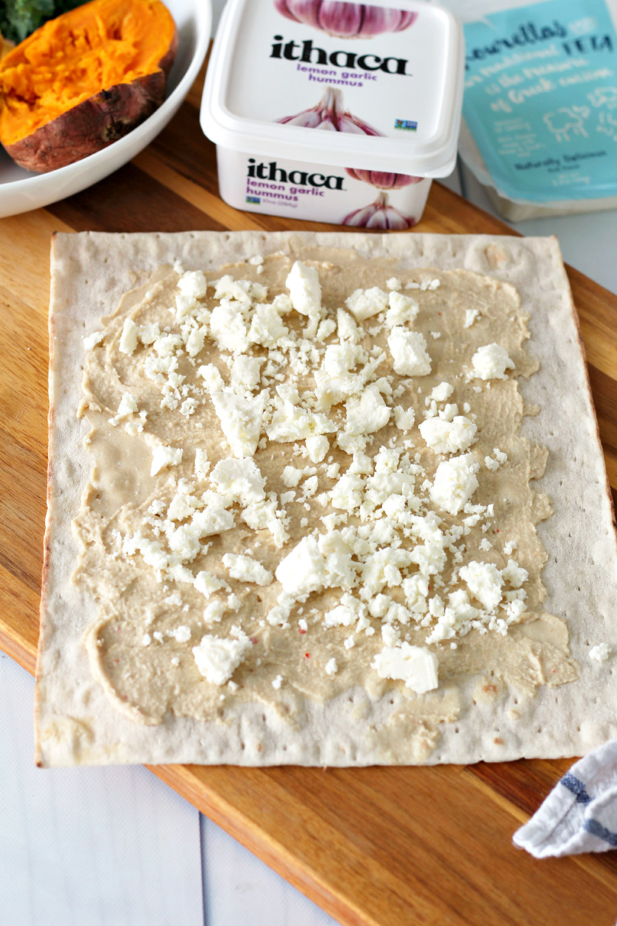 Lavash flatbread spread with lemon garlic hummus and sprinkled with feta cheese.