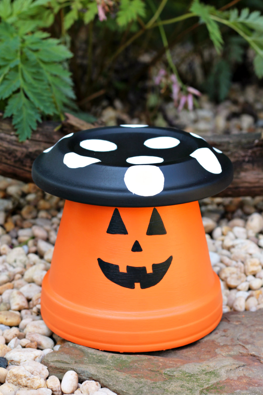 Front view of Halloween Clay Pot Toadstool sitting in rock garden.
