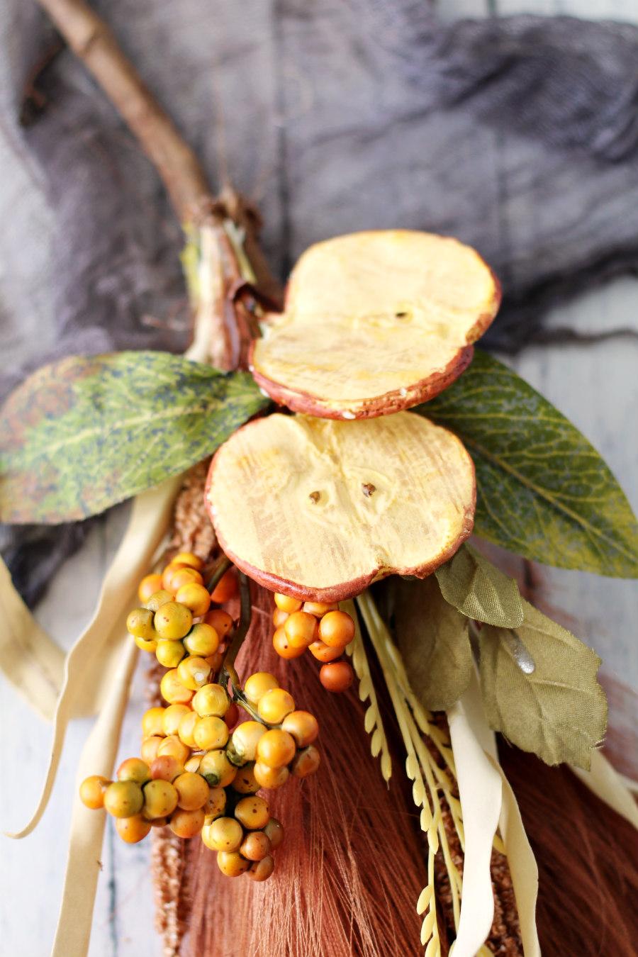 Close up photo of fall floral picks hot glued onto a pampas grass broomstick.