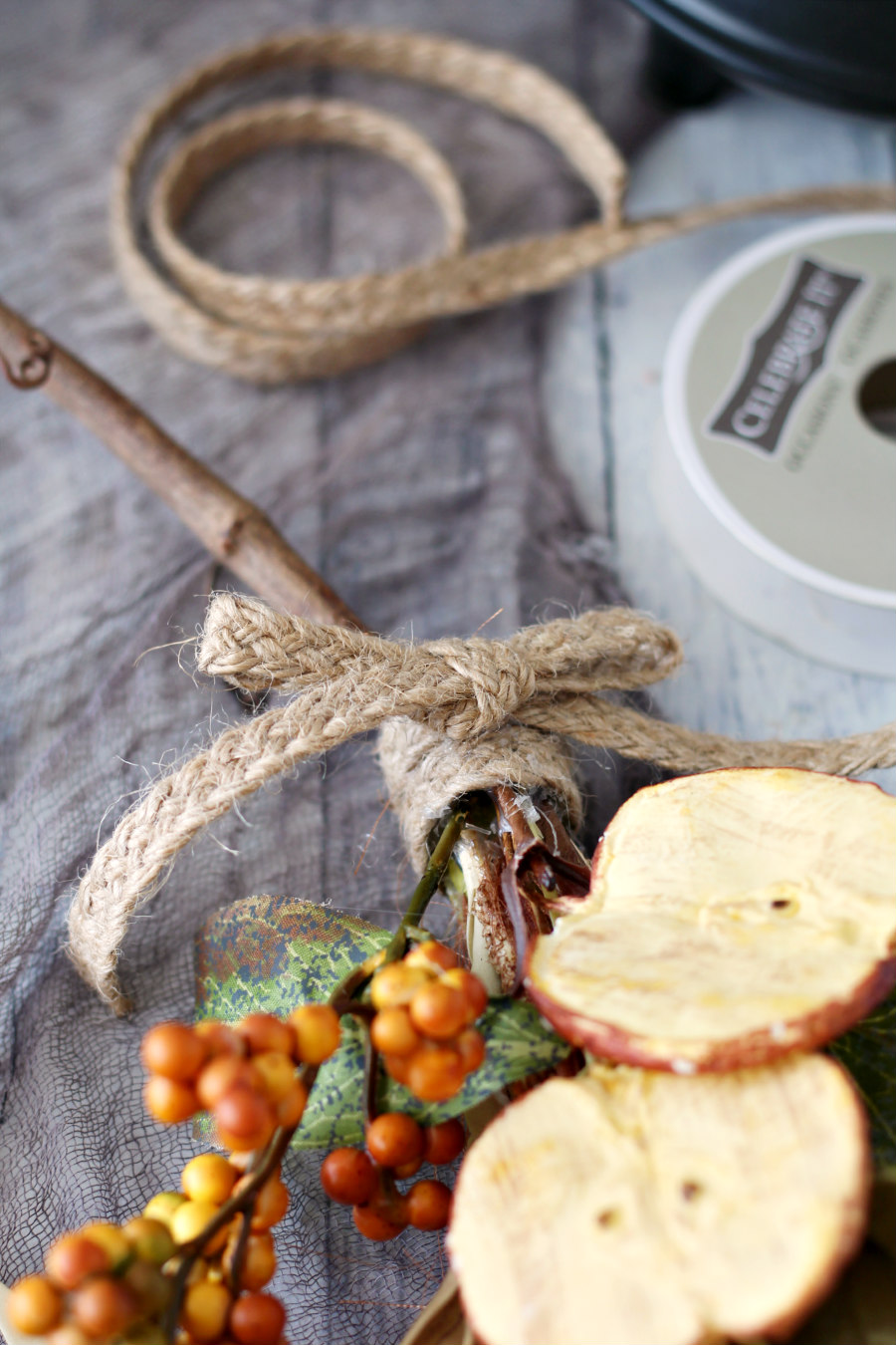 Jute ribbon tied around pampas grass broom embellished with floral picks.