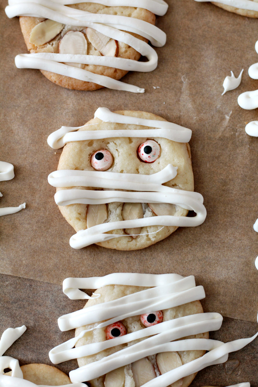 Easy Mummy Sugar Cookies on parchment paper drizzled with white candy melts.