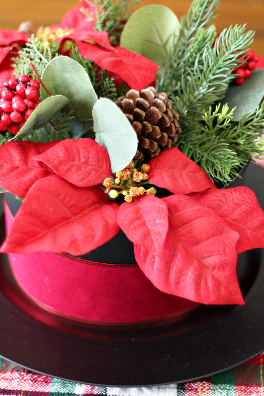 Close up of poinsettia flowers and seasonal greenery inside Snowman Hat Floral Centerpiece.