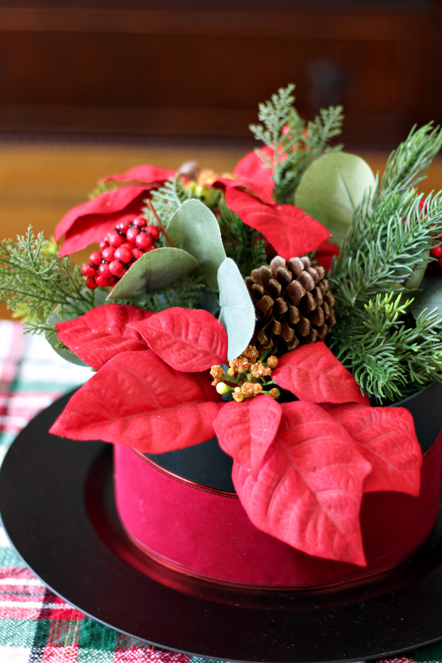 Cut off photo of Snowman Hat Floral Centerpiece on holiday plaid table runner.