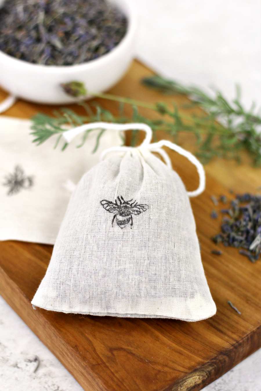 Dried Lavender Sweet Floral Fragrance Sachet - Bumble Bee Stamped Muslin Bag from Holoka Home on Etsy. Dried lavender sits around muslin bag on wooden board.