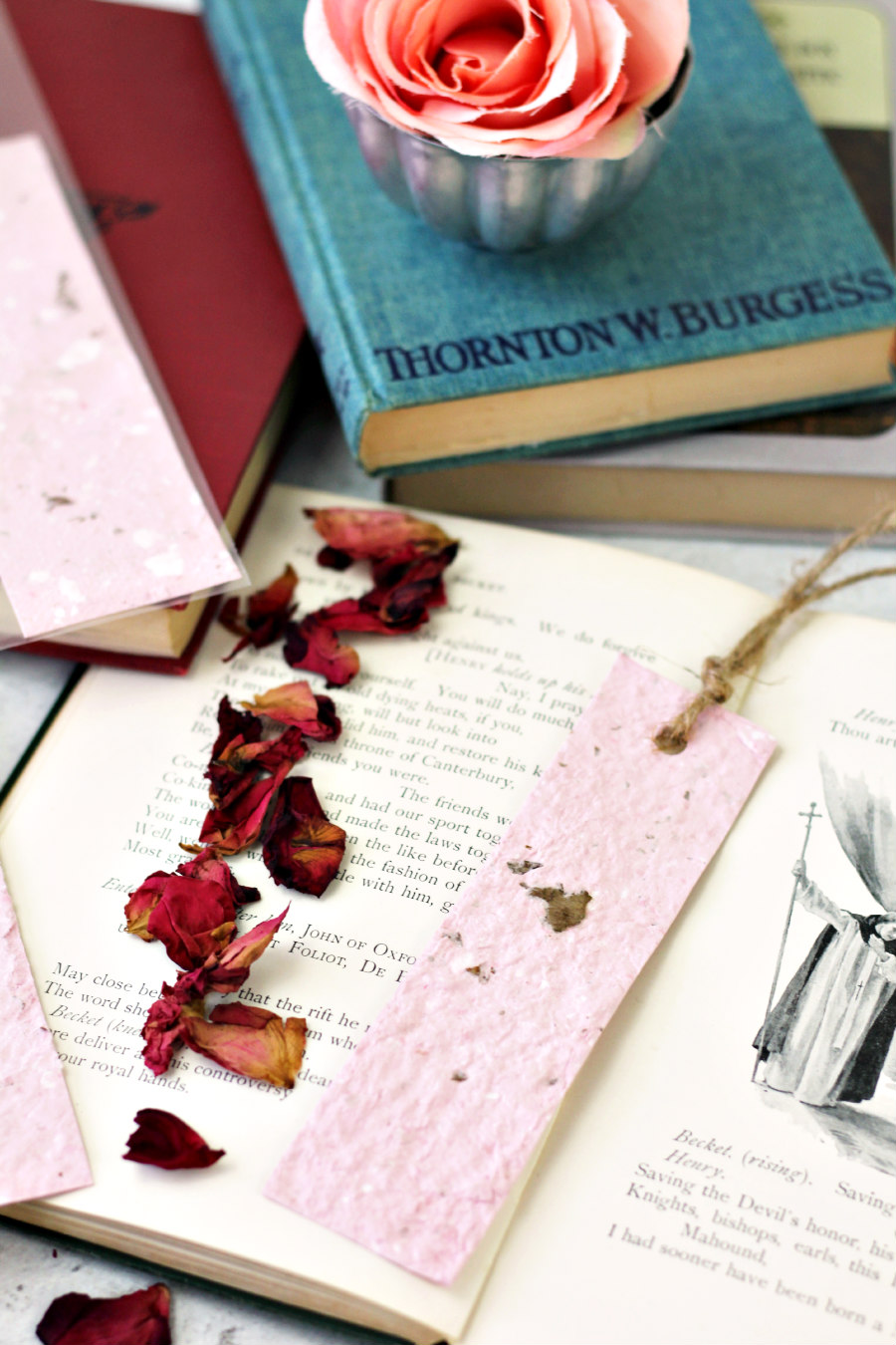 Floral Rose Recycled Upcycled Paper Handmade Bookmark - Dried Flowers - Cardstock - Book Lover - Reader from Holoka Home on Etsy. Pink paper bookmark sits on top of old open book with dried rose petals next to it.