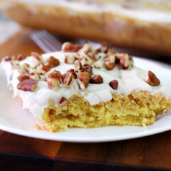Horizontal photo of Hummingbird Pudding Dump Cake slice on small white plate. Plate sits in front of baking pan.