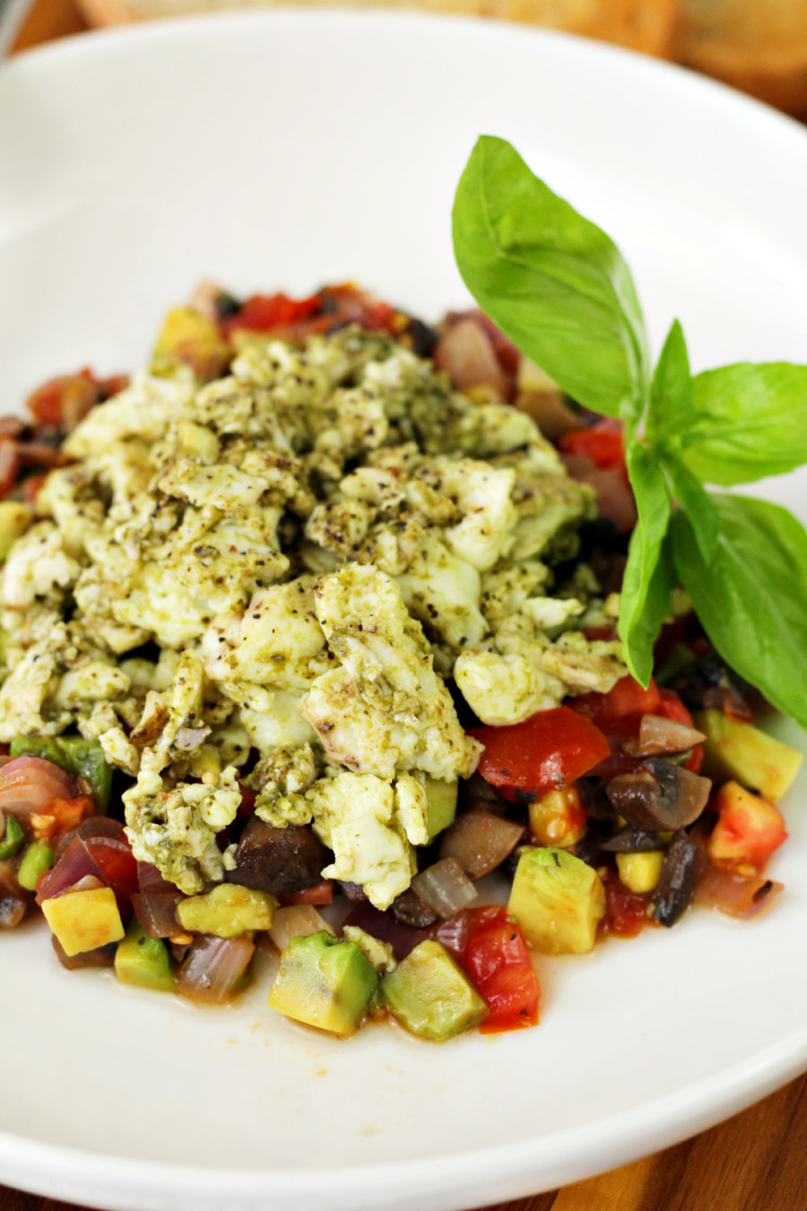Pesto Infused Egg White Skillet served in white plate and garnished with fresh basil leaves.  Plate sits on wooden board.