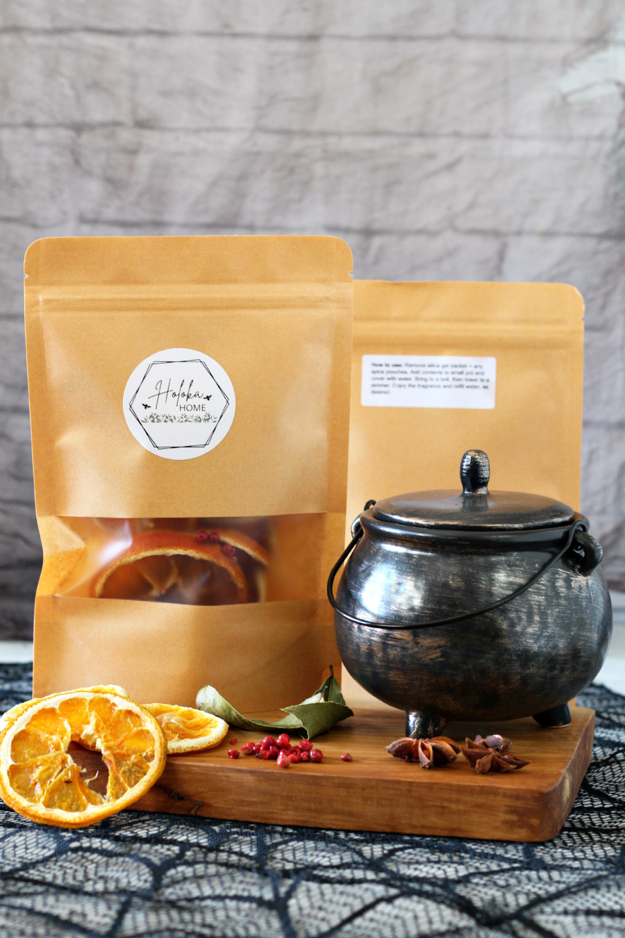 Haunted Harvest simmer pot kit packages sit on wooden board with small cauldron and simmer pot ingredients.