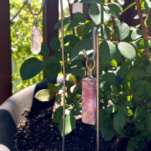 Clear quartz and amethyst crystal garden stakes sit in potted rose planter.
